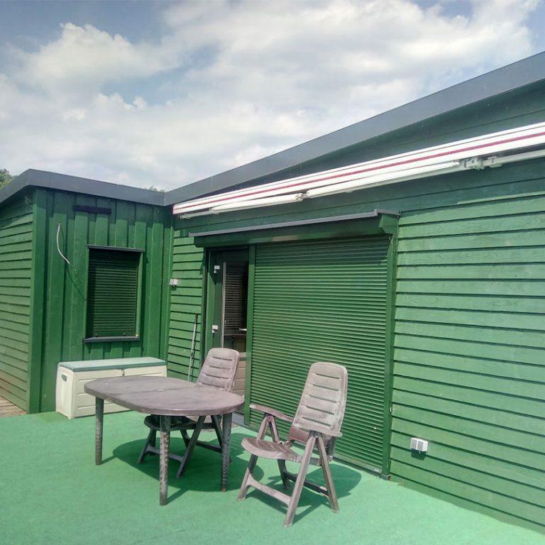 Gartenmöbel auf Bootshaus mit grünem Boden und grünen Fronten