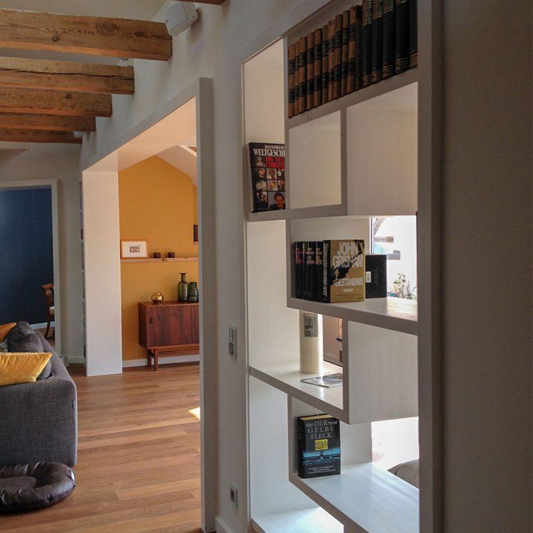 Offenes Einbauregal in modernem Wohnzimmer Stilvolles Einbauregal nach Maß mit asymmetrischen Fächern, integriert in eine Wand mit Holzbalkendecke und warmem Holzfußboden.