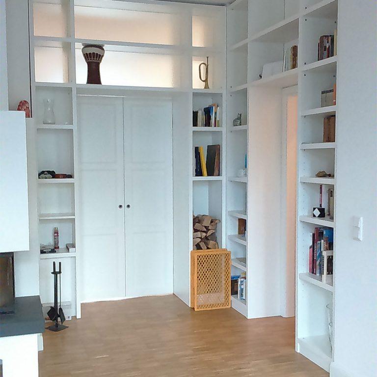 Weißes Einbauregal mit Flügeltüren und offenen Regalfächern Elegantes Einbauregal nach Maß mit Flügeltüren, offenen Fächern für Bücher und Dekor, und einem Holzlagerplatz.