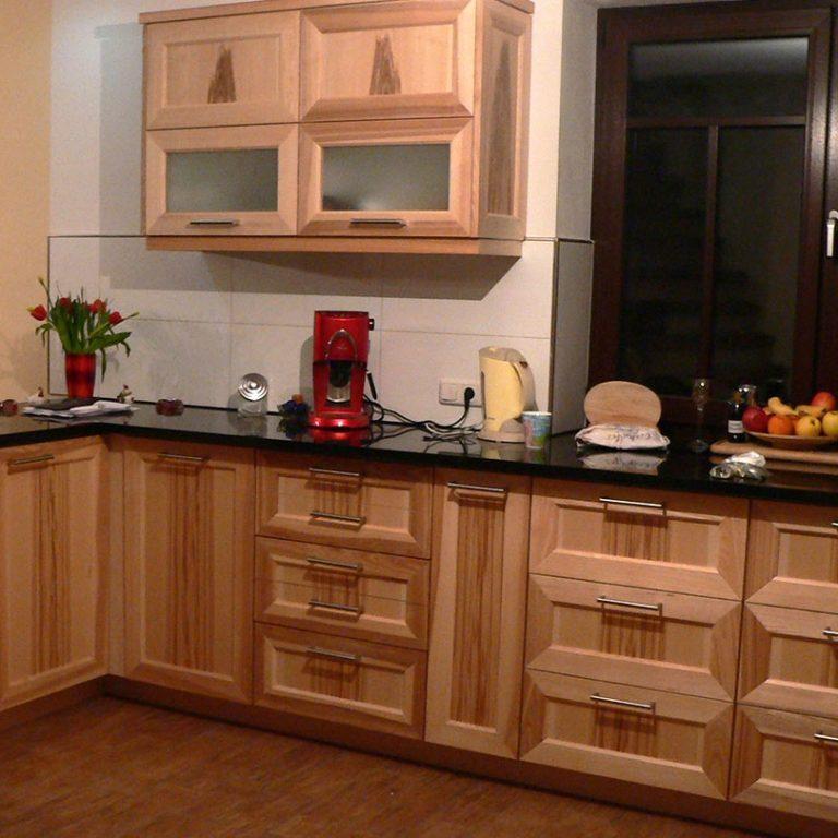 Maßgefertigte Küche mit Holzschränken und Glasdetails Moderne Küche nach Maß mit Holzschränken, schwarzen Arbeitsplatten und Hängeschränken mit Glaseinsätzen.