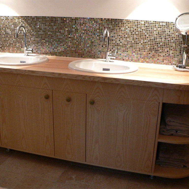 Maßgefertigter Waschtisch mit Doppelwaschbecken Eleganter Waschtisch aus Holz nach Maß mit zwei Waschbecken, offenen Regalfächern und einer Mosaik-Rückwand für ein stilvolles Badezimmer.