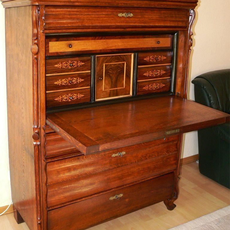 Aufwendig restaurierter antiker Sekretär mit reich verzierten Holzdetails, Klappschreibtisch und dekorativen Schubladen, ideal für klassische Wohnräume.