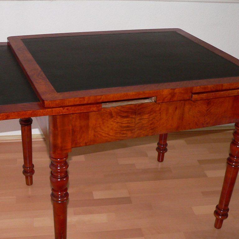 Restaurierter antiker Tisch mit ausziehbarer schwarzer Oberfläche und gedrechselten Beinen, perfekt für ein elegantes Ambiente.