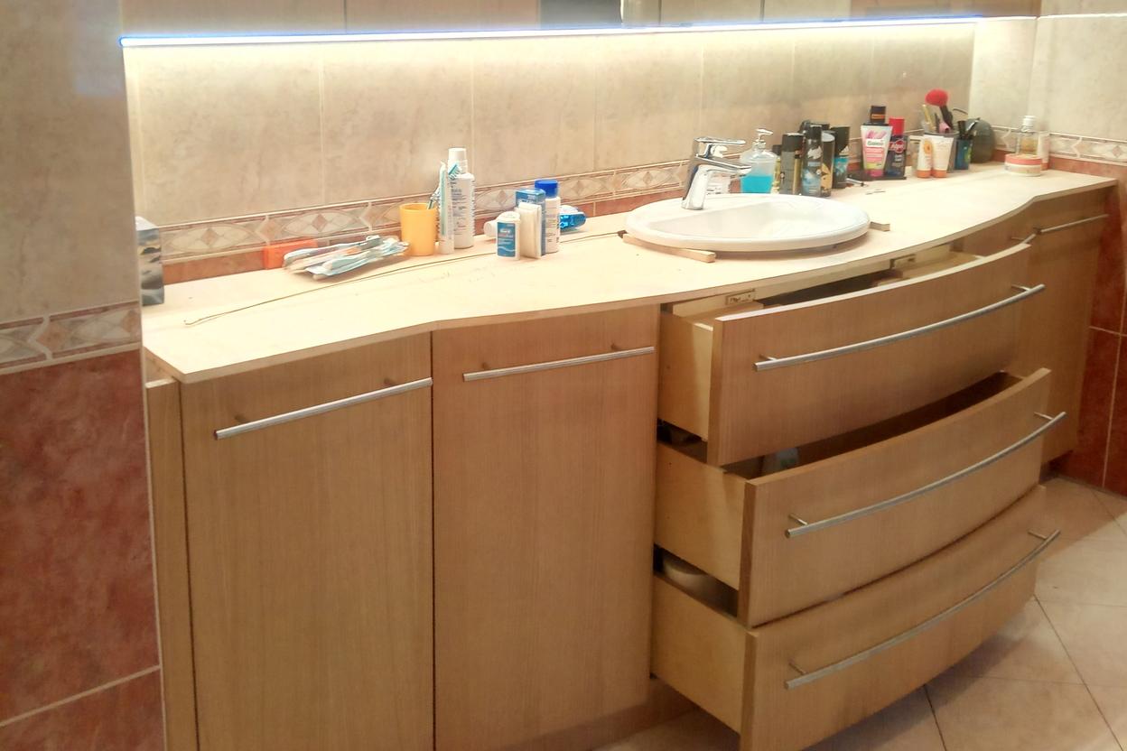 Badezimmerschrank mit offenen Schubladen und LED-Spiegel Moderne Badezimmerschranklösung mit geschwungenen Holzschubladen, LED-beleuchtetem Spiegel und viel Stauraum für Pflegeprodukte.