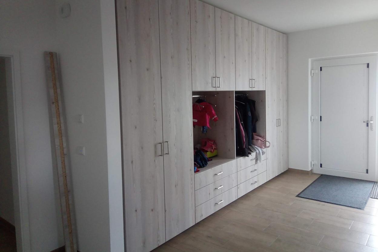 Gro&szlig;er Wandschrank nach Ma&szlig; in Holzoptik mit offenen Garderobenf&auml;chern, Schubladen und geschlossenen T&uuml;ren f&uuml;r optimalen Stauraum im Eingangsbereich.