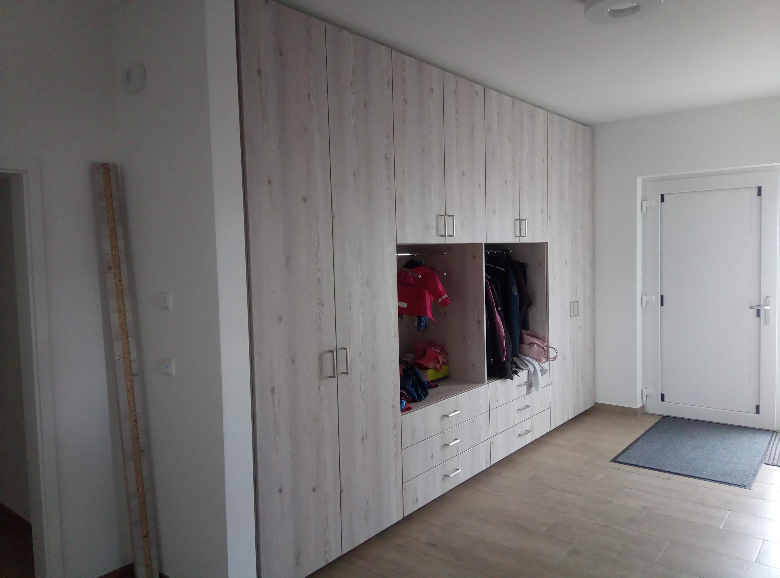 Großer Wandschrank nach Maß in Holzoptik mit offenen Garderobenfächern, Schubladen und geschlossenen Türen für optimalen Stauraum im Eingangsbereich.