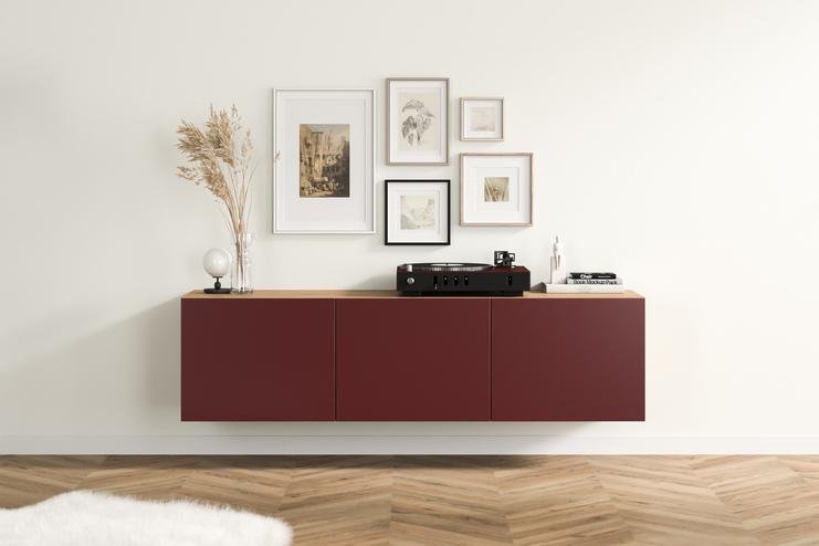Elegantes, burgunderrotes Hängeboard nach Maß mit glatten Fronten und Holzakzenten, angebracht unter einer kunstvollen Bildergalerie im Wohnzimmer.