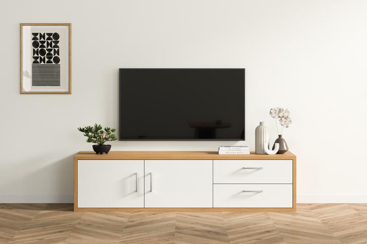 Eine maßgeschneiderte Kommode in hellem Holzfinish mit weißen Fronten, darunter ein TV-Gerät, begleitet von dekorativen Vasen und Büchern, in einem hellen Wohnraum.